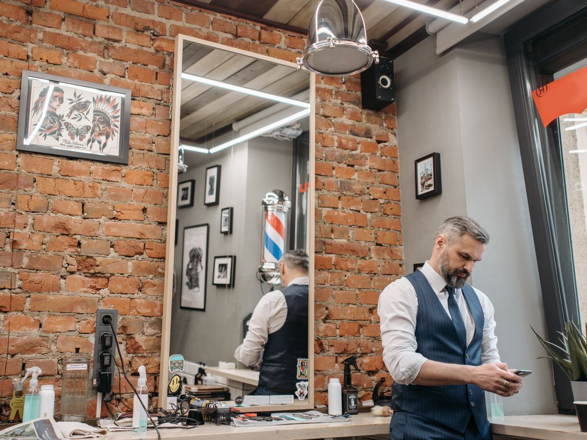 Barbeiro em ambiente de barbearia com parede de tijolinho